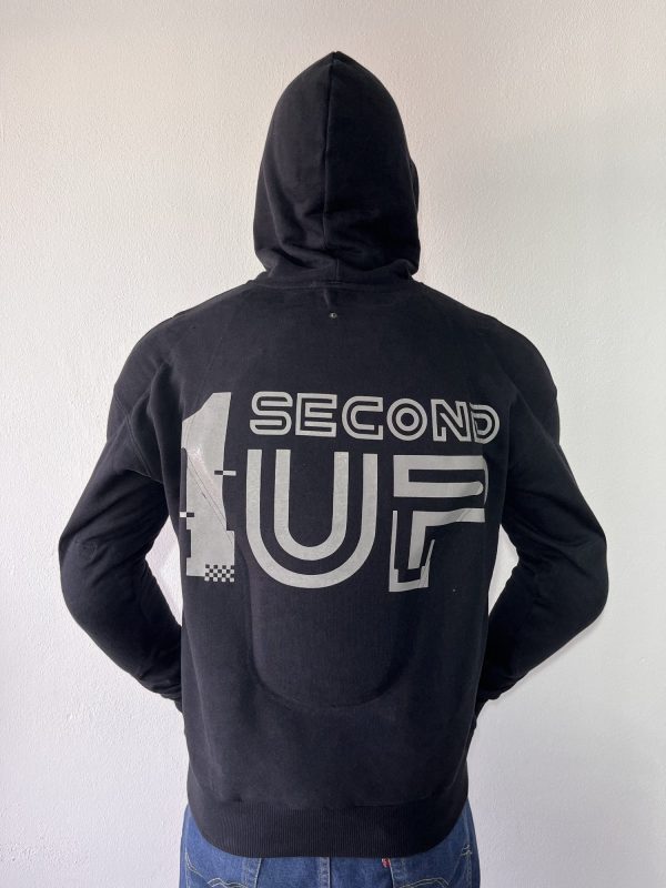 Back view of a Second 1UP black motorcycle hoodie with a large reflective logo logo for visibility, worn by a motorsports rider in a helmet