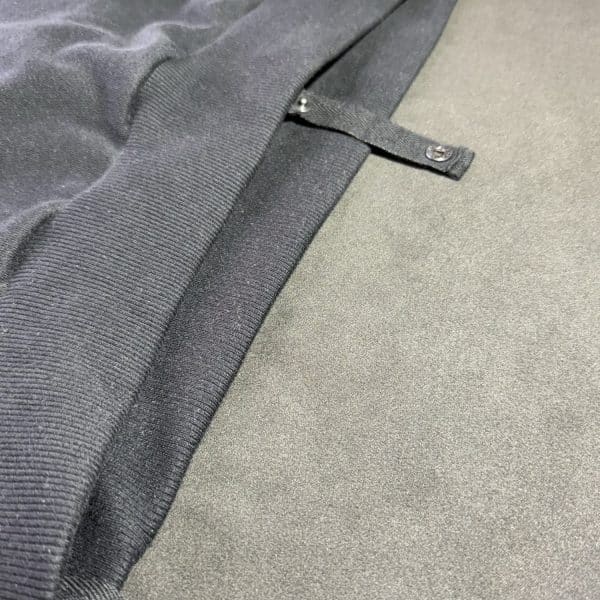 Detailed view of a Second 1UP black motorcycle hoodie with a concealed buttons for trousers, crafted for motorsports functionality