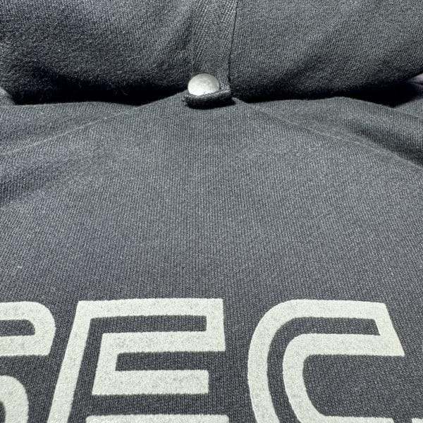 Detailed view of a Second 1UP black motorcycle hoodie with a concealed button, crafted for motorsports functionality