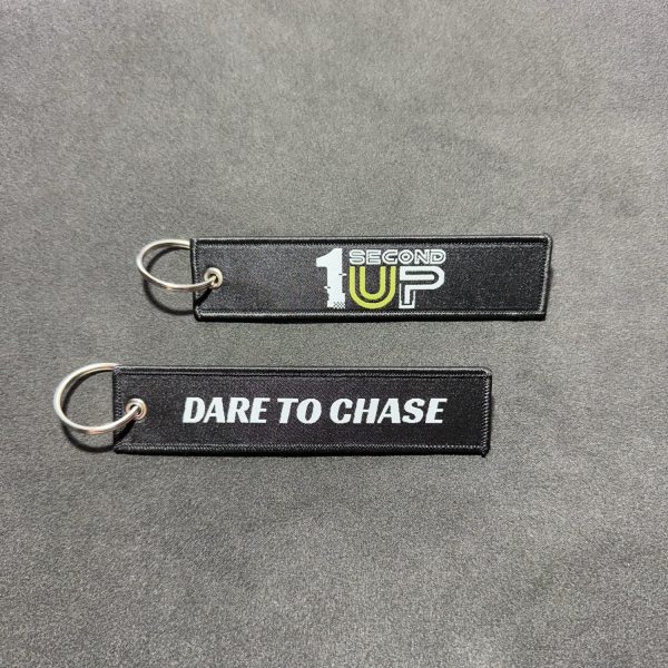 Set of black embroidered Second 1UP motorcycle keychains with 'Dare to Chase' and logo, perfect for motorsports enthusiasts