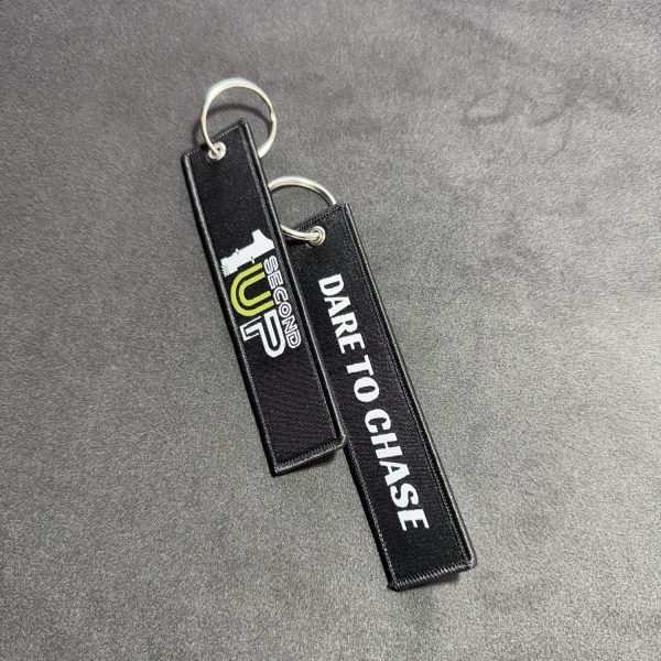 Set of black embroidered Second 1UP motorcycle keychains with 'Dare to Chase' and logo, perfect for motorsports enthusiasts, sideways